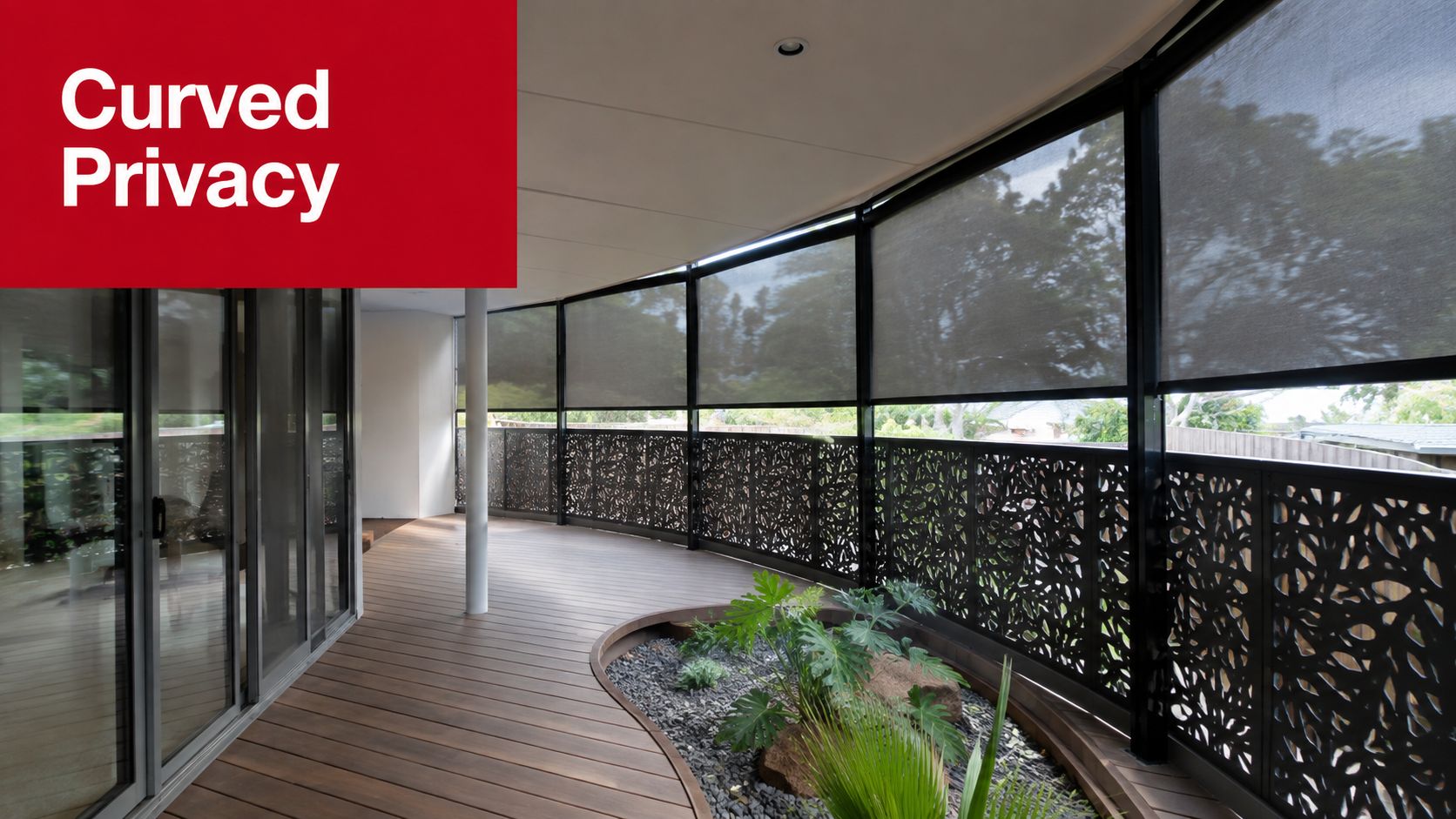 A modern curved wooden deck featuring decorative metal privacy screens and outdoor roller blinds overlooking the backyard.